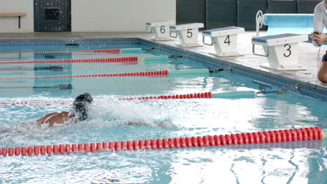 a caucasian coach monitors a swimmer''s performance