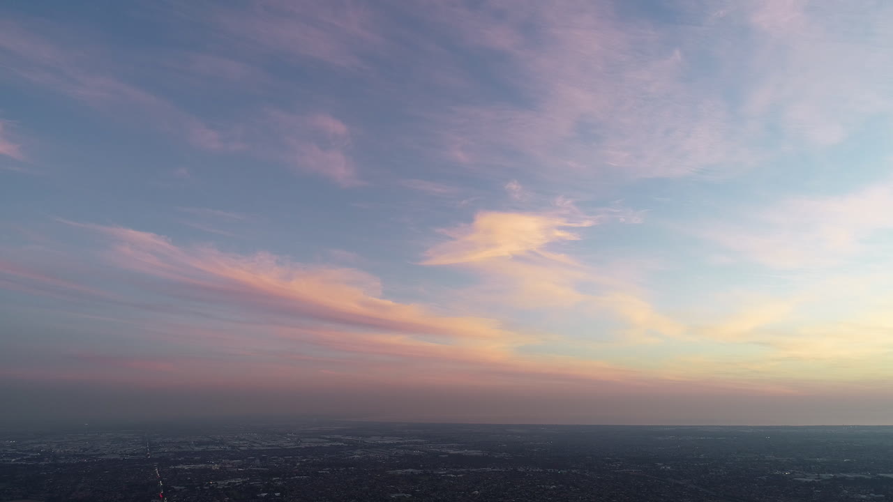 Luftfoto af en betagende solnedgang over et forstadsområde, der bevæger sig langsomt mod venstre