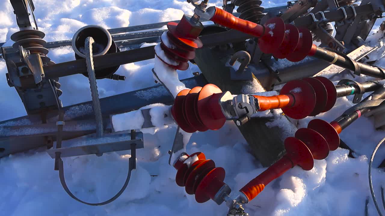 Top down cinematic view of railway overhead suspension insulators resting in snow with strong winter sunlight casting detailed shadows