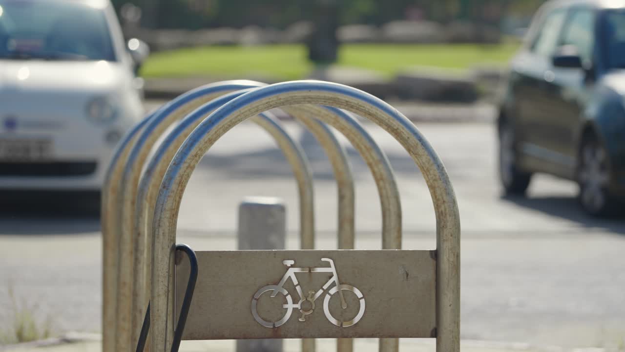 Close up on metal public bicycle parking stand in street in city or neighborhood. Sunny day with no bikes attached and locked on stand. Icon of bicycle on metal rod by parking lot. Green commute