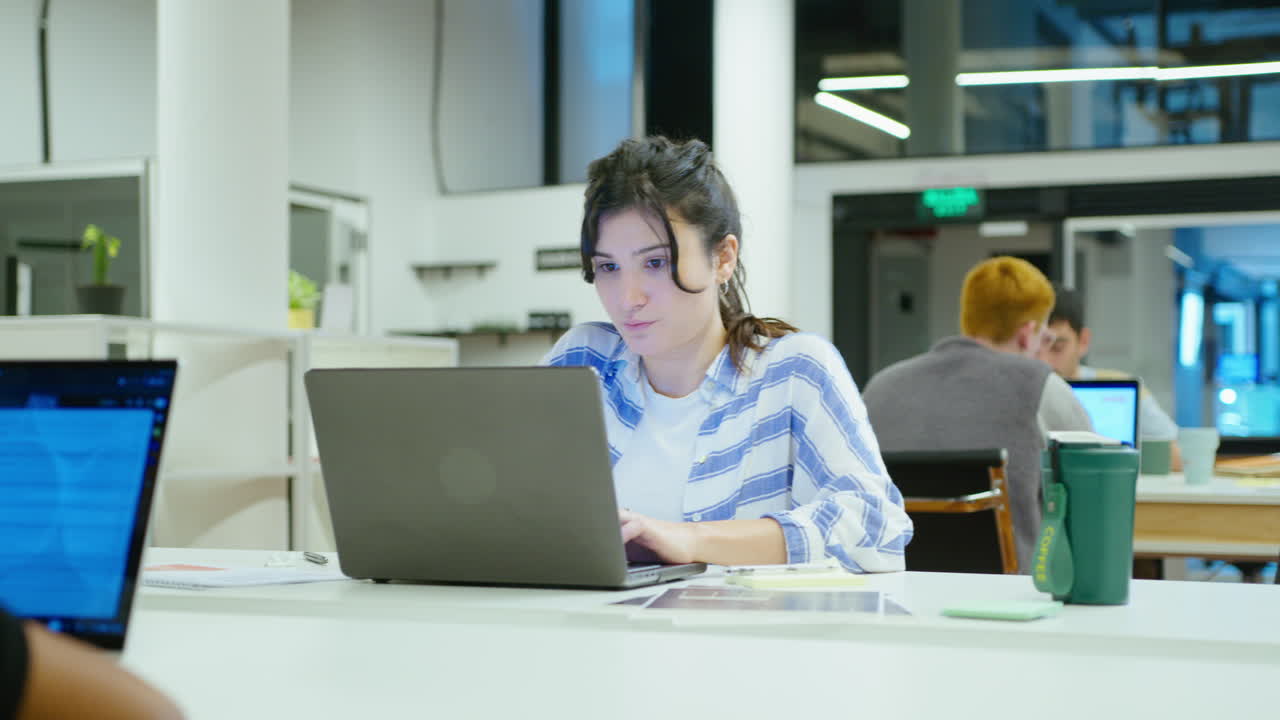 Concentrated Girl Using Laptop at Desk in the Office