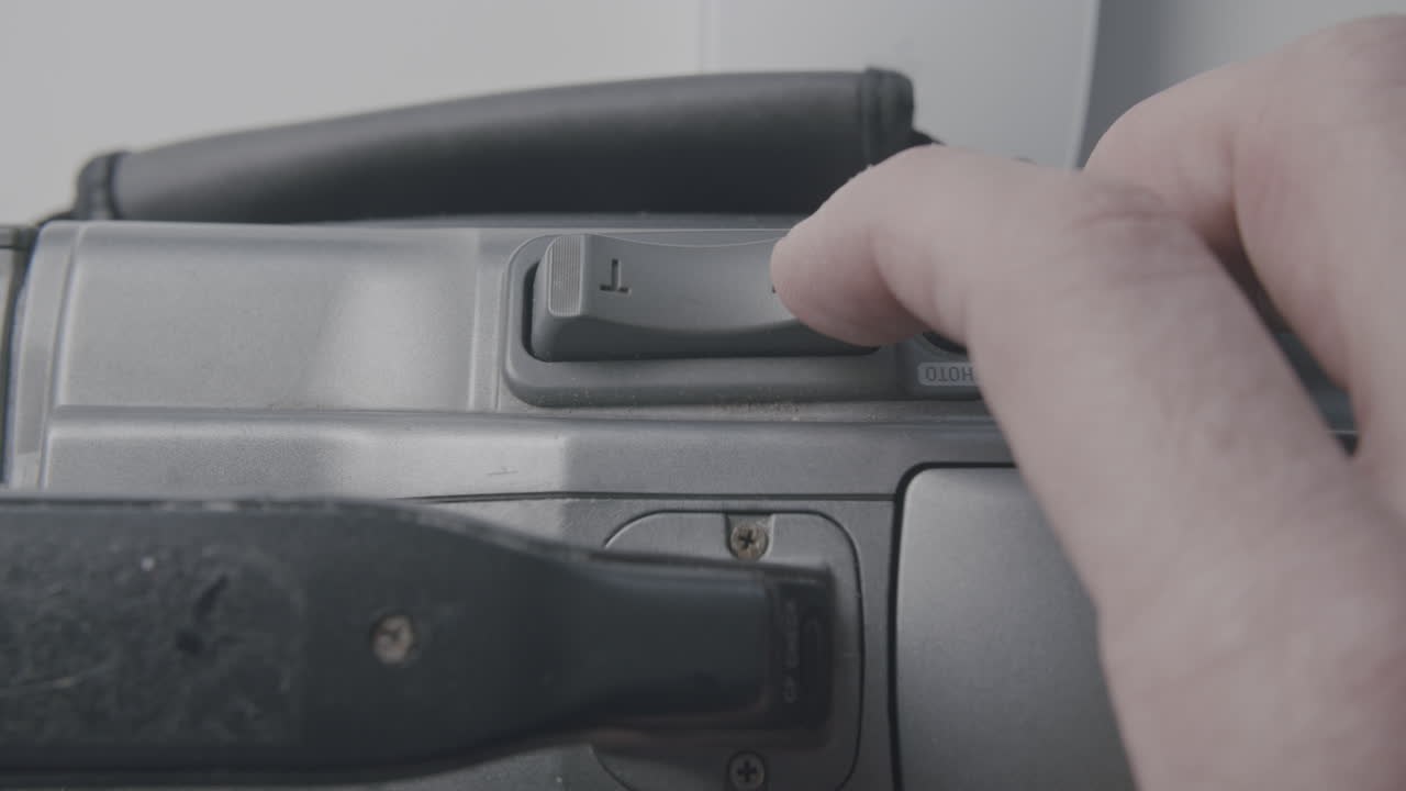 mano caucásica empujando el control de zoom en la antigua cámara mini dv