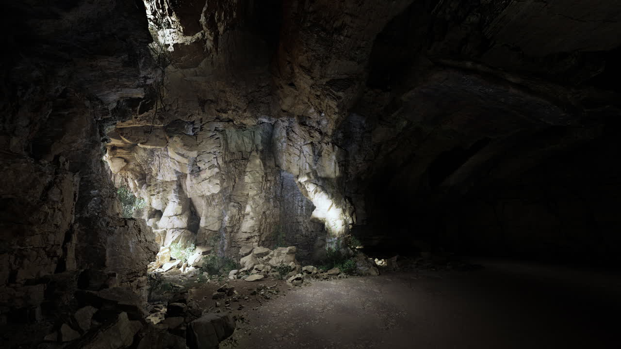Light illuminates textured rock formations within a dark cave space