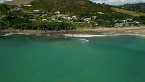 Cinematic-aerial-pan-over-surfers-waiting-in-line-for-the-next-wave-to-break-in-small-New-Zealand-town