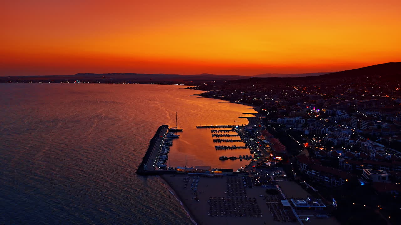 Vacker utsikt över semesterorten i skymningen. Drönarfilm över yachtklubben nära havskusten. Fantastisk orange himmel i bakgrunden.