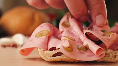 preparing a ham and olive sandwich