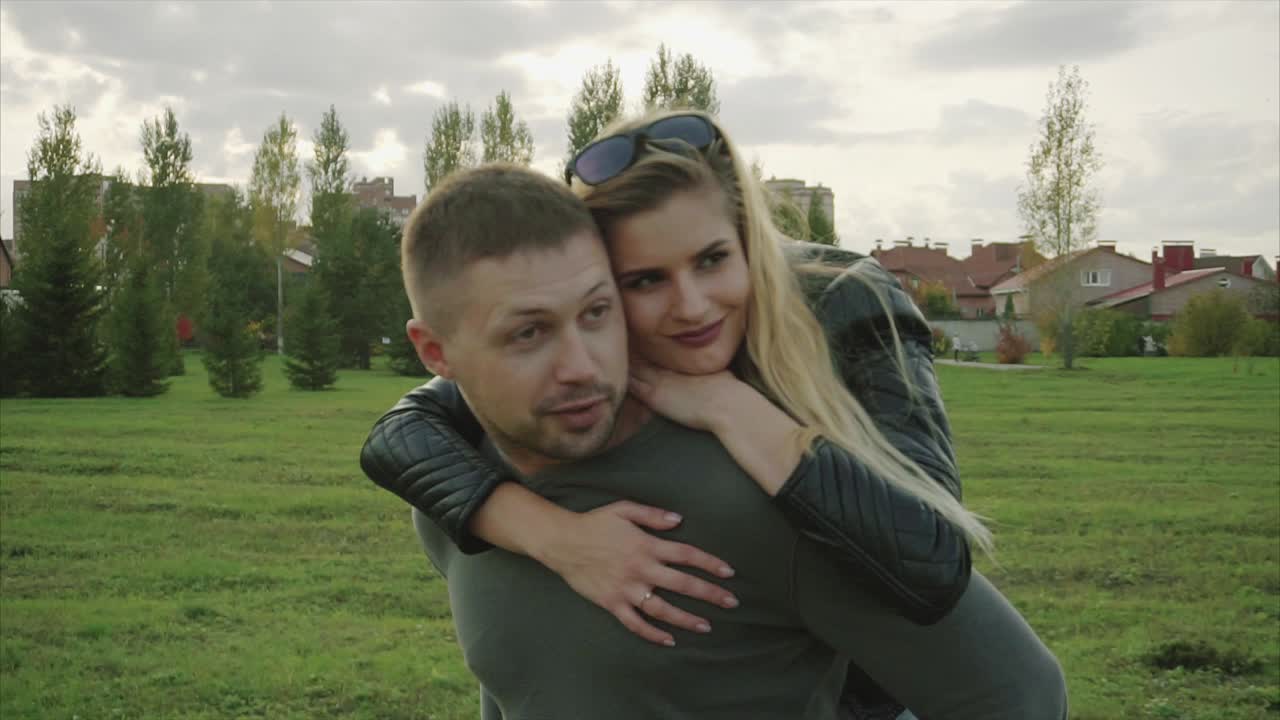 한 부부가 공원에서 돼지 등에 타고 즐기고 있다