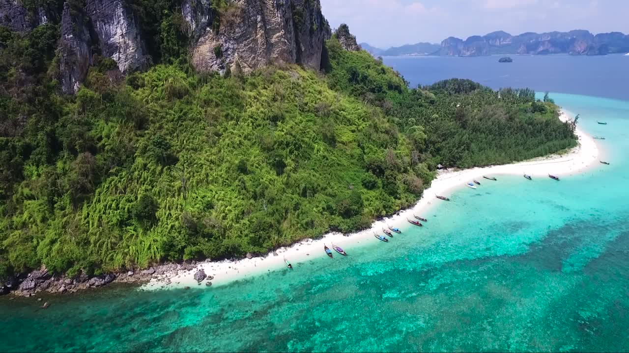 보트가 해안에 정박해 있는 작은 열대 섬의 놀라운 공중 촬영