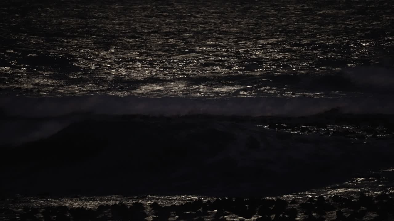 olas rompiendo en la noche con el reflejo de la luz de la luna en el agua