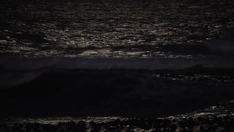 waves breaking at night with the reflection of the moonlight on the water