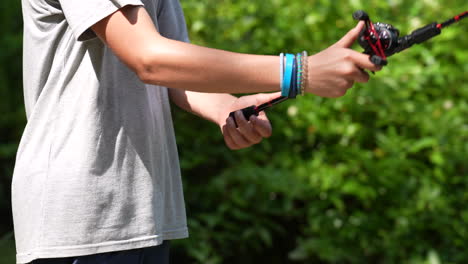 Closeup-spinning-reel-held-by-teen-fishing-on-a-summer-afternoon