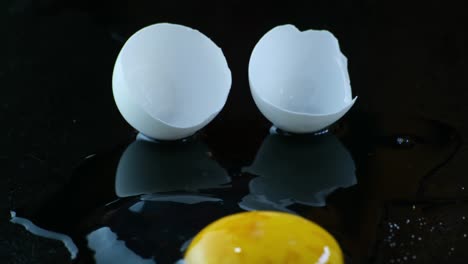 tilt up, uncooked egg with cracked white eggshell over black background