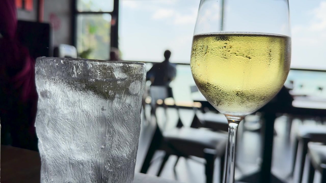 Primo piano di condensa su un bicchiere da vino e acqua ghiacciata in un resort tropicale.