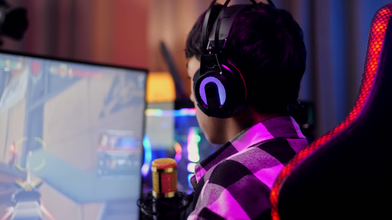 Primo Piano Vista Posteriore Di Un Ragazzo Streamer Asiatico Che Si Sente Deluso Per Aver Perso La Partita Sul Computer Personale. Live Stream Di Videogioco, Scrivania Illuminata Da Striscia LED RGB.