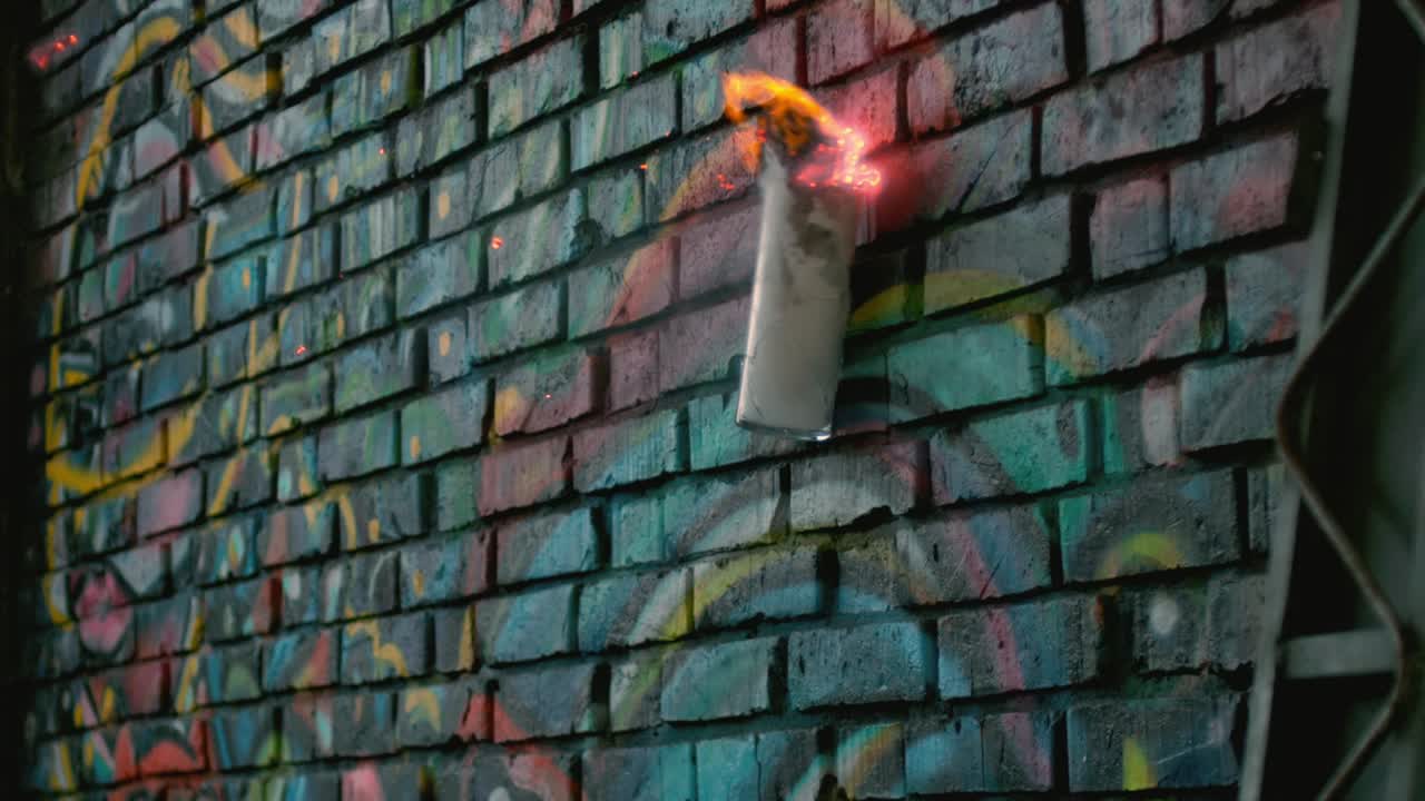 una botella en llamas explota contra una pared dura, desintegrándose en cámara lenta