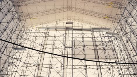 tilt up wide angle shot of a large tent structure held up by scaffold covering an old ship