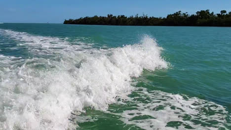 dolphin jumps close behind motor boat as it swims and follows the waves from the engine in the ocean