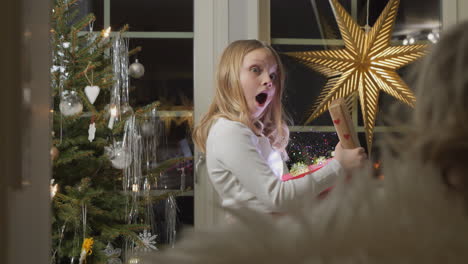 young girl opening a magical sparkly christmas gift in awe, warm indoor holiday setting