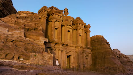 woman looking on the ancient building od ad deir monastery with nabataean style in petra, jordan