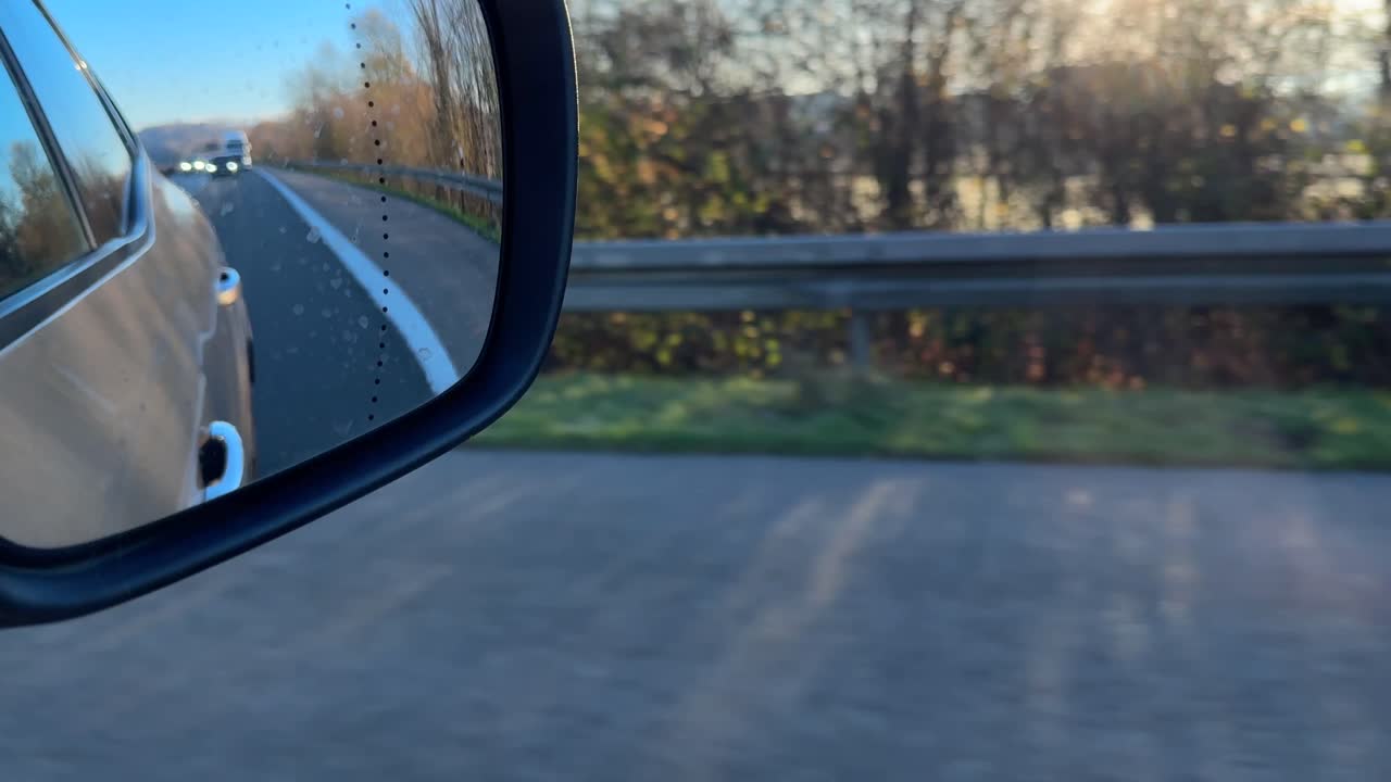 Vista dallo specchietto retrovisore di un viaggio in autostrada in una giornata di sole.