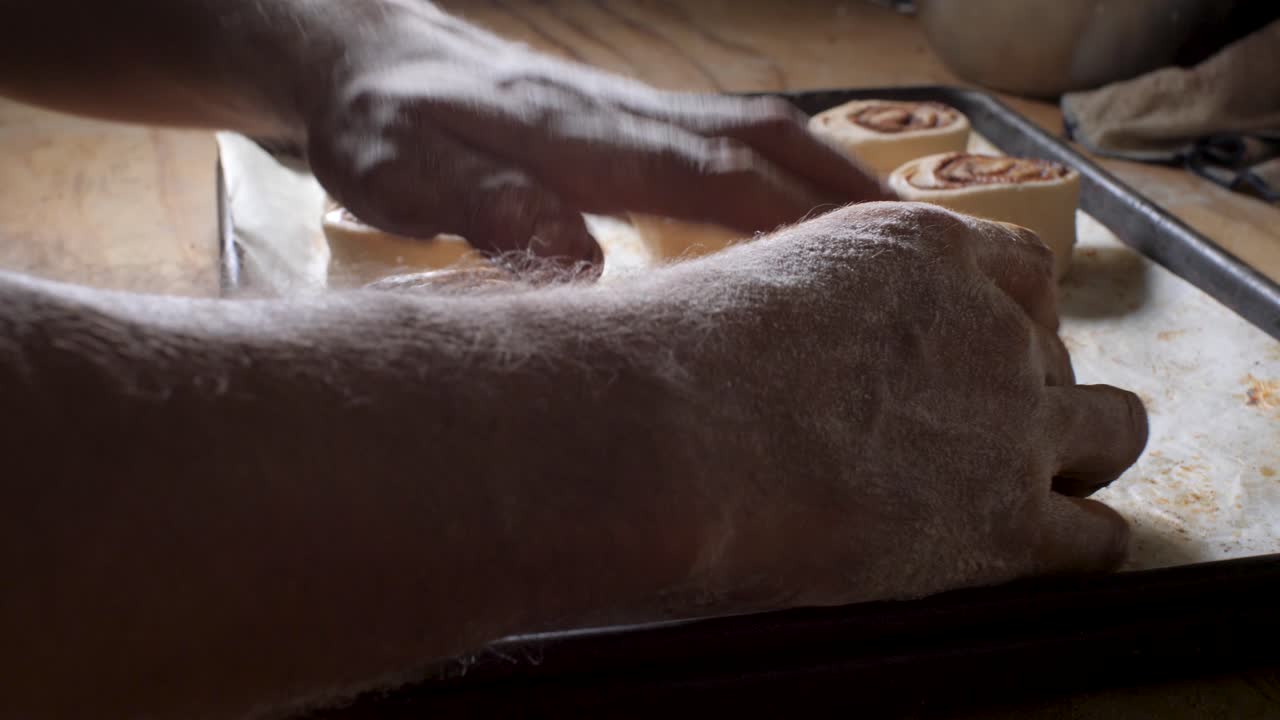 Latin American bakery worker puts on trays of cinnamon bread made with organic, gluten-free and vegan bread, small business vegan bakery in Mexico, closeup