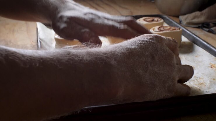 Latin American bakery worker puts on trays of cinnamon bread made with organic, gluten-free and vegan bread, small business vegan bakery in Mexico, closeup
