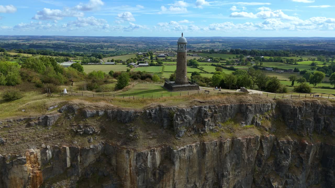 Drone capture of Crick Tower monument on elevated hill with sweeping views of valleys, meadows, and fields in Derbyshire