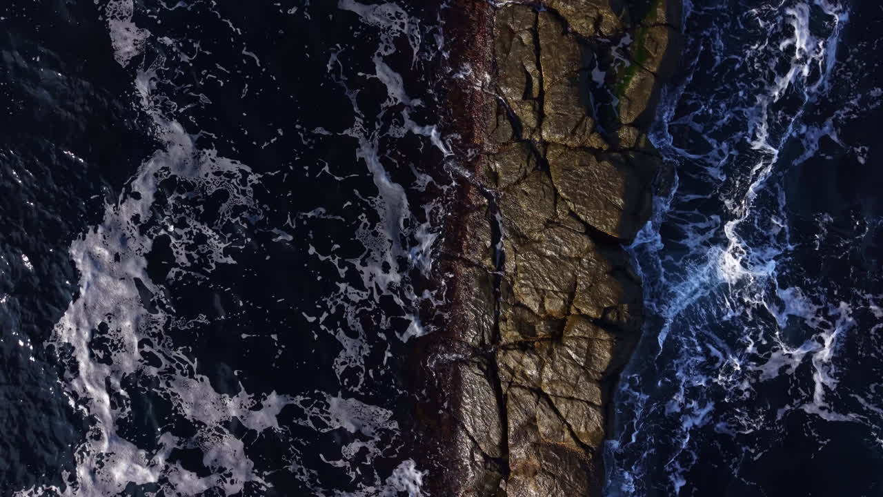 Waves crashing against a rugged shoreline, showcasing the dynamic beauty of nature as water meets stone during daylight