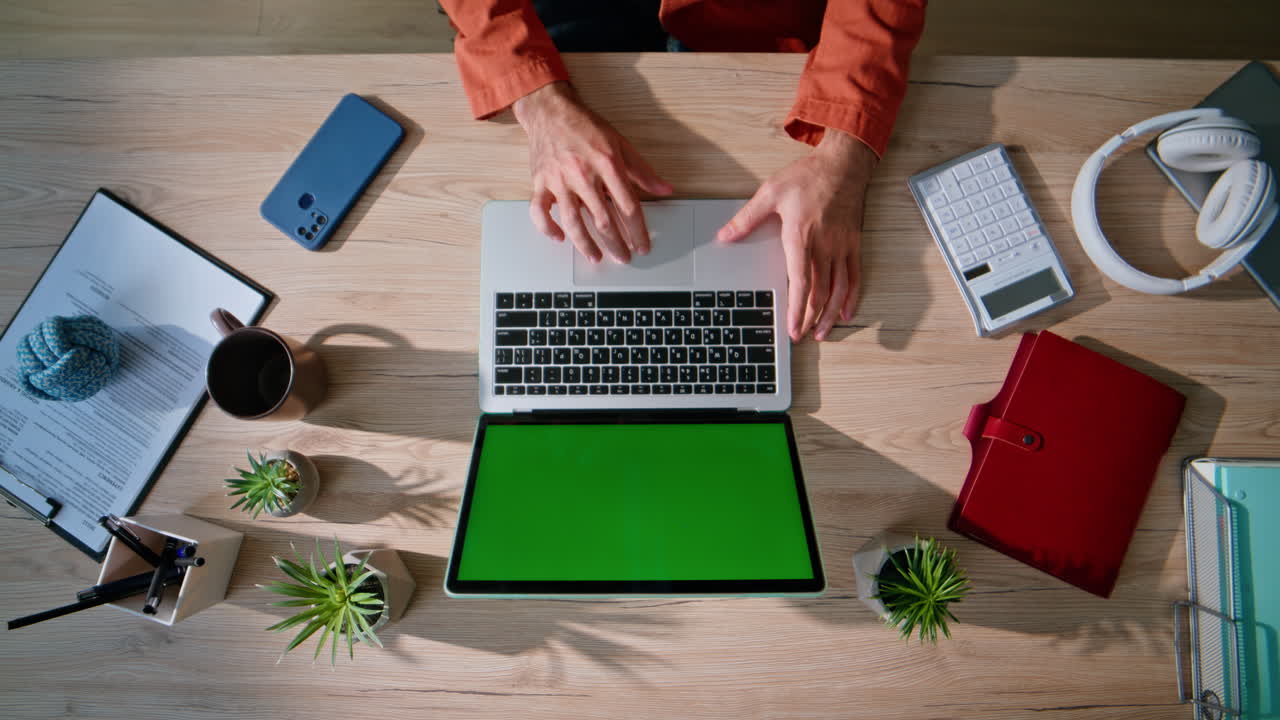 Professional hands working chroma key laptop in office environment top view