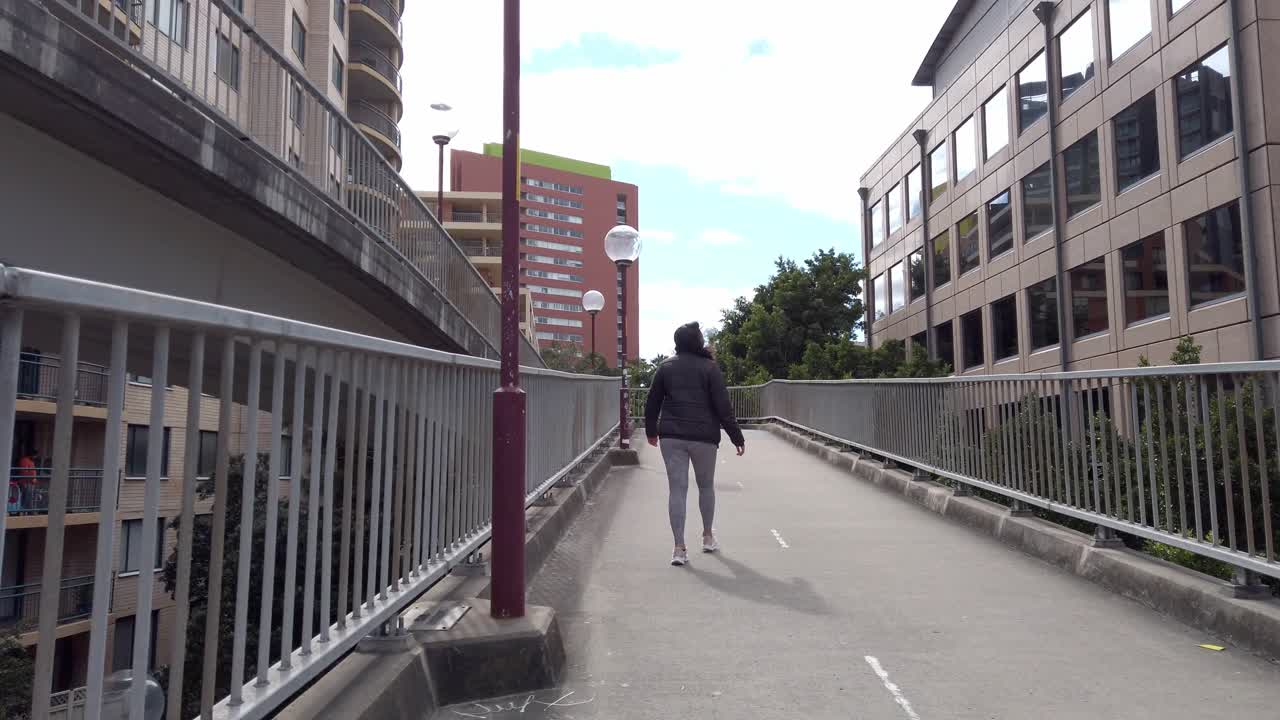 dama sola camina hacia el puente anzac en sydney nsw, australia - pov