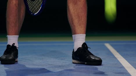 tennis player holding the ball and getting ready to serve. close-up feet tennis player preparing to serve. knocking the ball on the court and hitting the racket