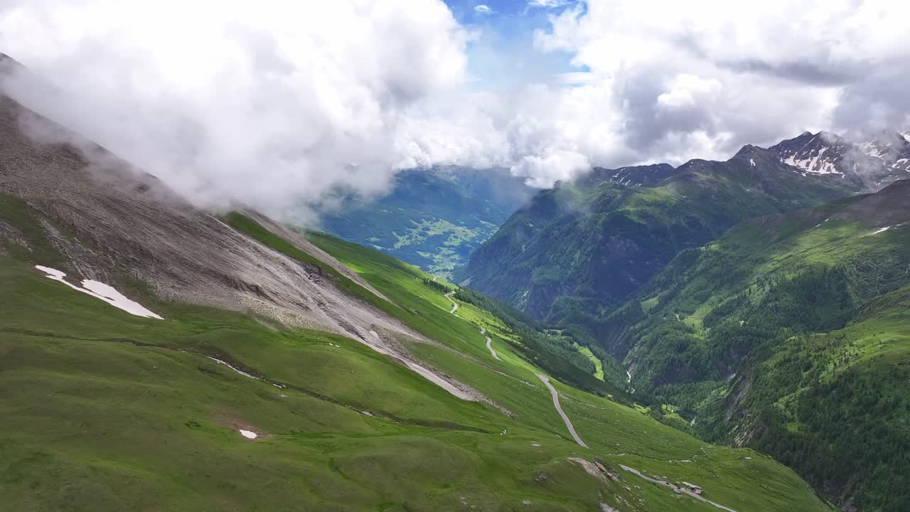 Aerial View of a Winding Mountain Road Through a Green Valley