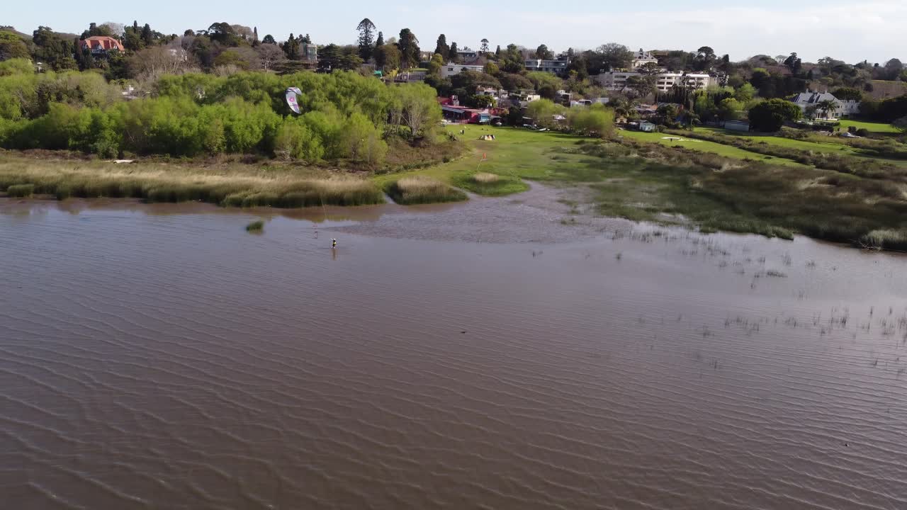 toma aérea de una persona practicando kitesurf en el río de color marrón de buenos aires durante el día soleado