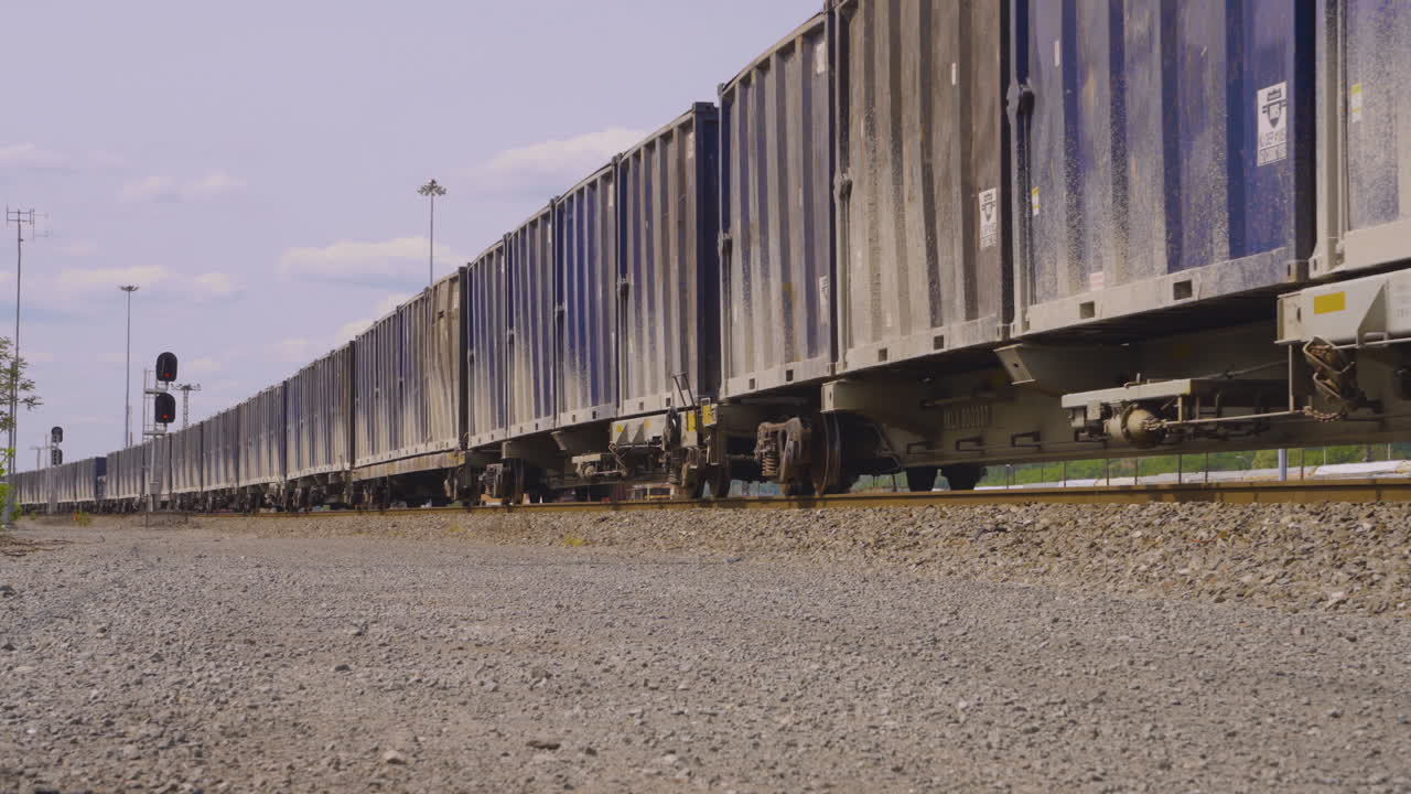 vista a nivel del suelo de un largo tren de vagones de caja azul rodando lentamente a lo largo de las vías del tren en el cinturón de óxido de ohio conocido como youngstown