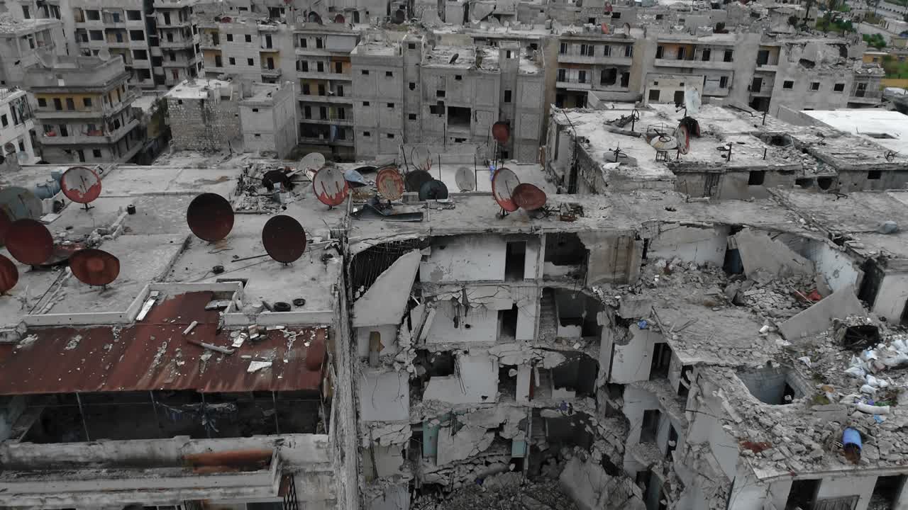 vista aérea sobre los techos de los edificios en alepo, siria. hay una antena oxidada con el tiempo en el techo, los edificios están en ruinas 4k