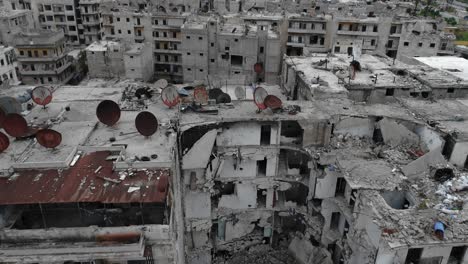 aerial view above roofs of buildings in aleppo, syria. there is antenna rusted with time on the rooftop, the buildings are in ruins 4k