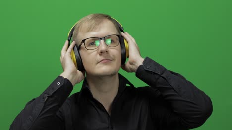 Guy-listens-to-music-in-wireless-yellow-headphones-and-dances.-Chroma-key