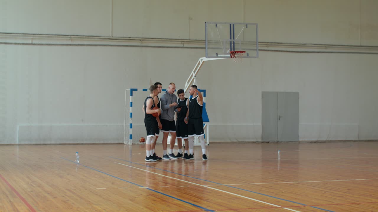 Una squadra di basket e l'allenatore discutono la strategia in campo