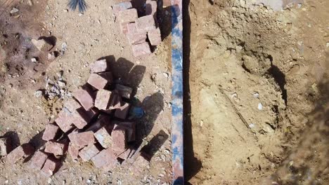 construction using earthen blocks, building the foundation of the house, workers work at a construction site in india, building a house with red stone , works using cement