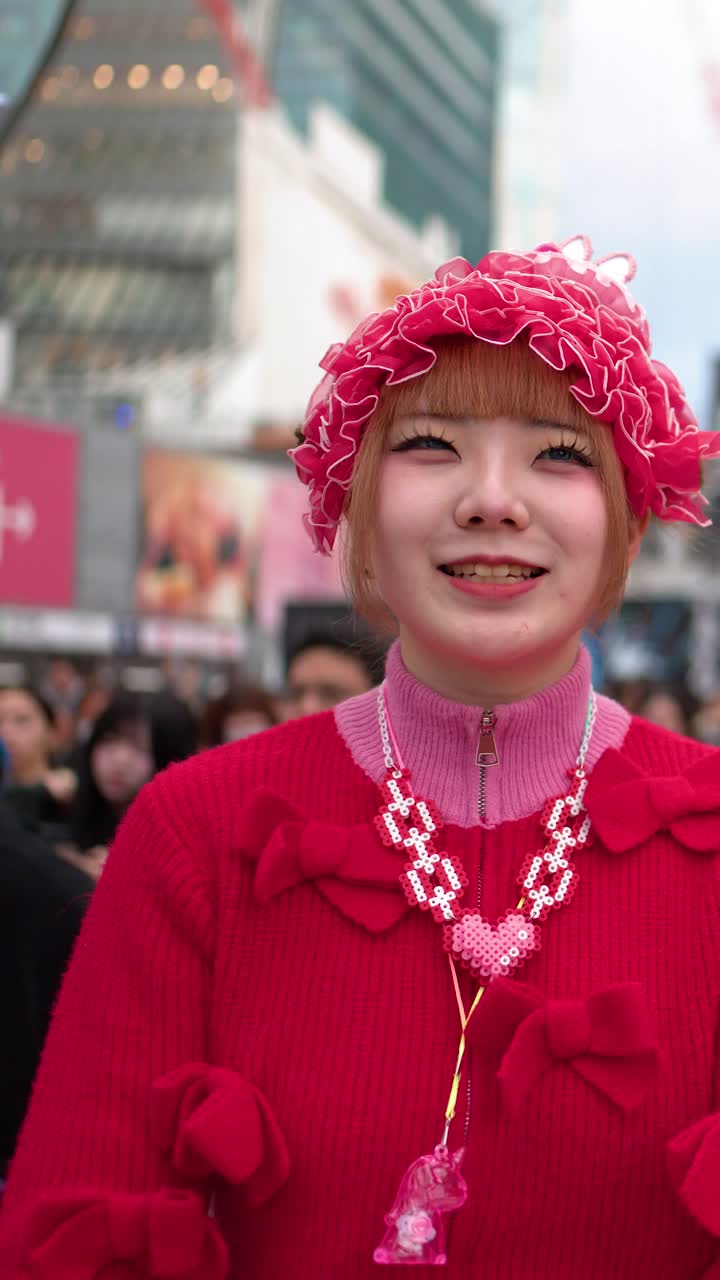 Een jonge vrouw gekleed in opvallende roze kleding in Harajuku-stijl roept en lacht in Shibuya.