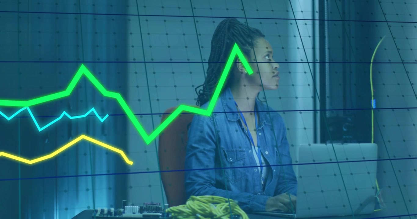 Ingegnere dei dati che digita su un laptop in un laboratorio blu, avviando linee di grafici colorate oscillanti per il monitoraggio.