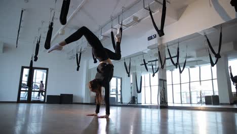 A Flexible Slender Acrobat Girl Doing a Handstand in a Modern Gym in the Middle of the Day. A flexible, slender acrobat girl doing a handstand in a modern gym in the middle of the day. Gymnastic training