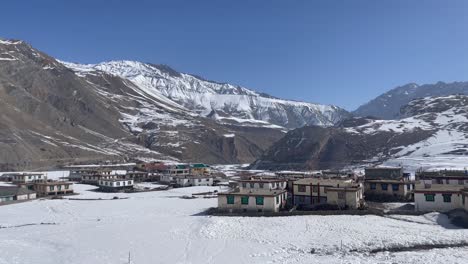 scenic view of houses at the foot of mountains in icy valley in himachal pradesh, india - panning shot