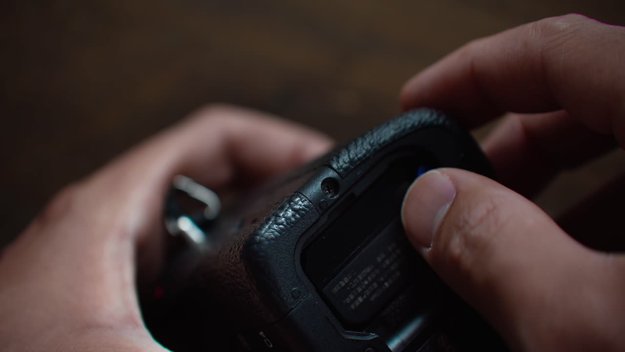 la mano dell'uomo rimuove la batteria della fotocamera per caricarla