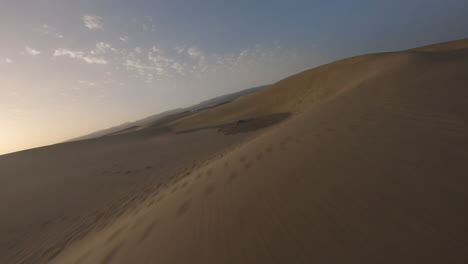 Vuelo-Aéreo-Rápido-Y-Bajo-Sobre-El-Agua-Del-Mar-Hacia-Las-Dunas-De-Arena-Al-Atardecer,-Maspalomas