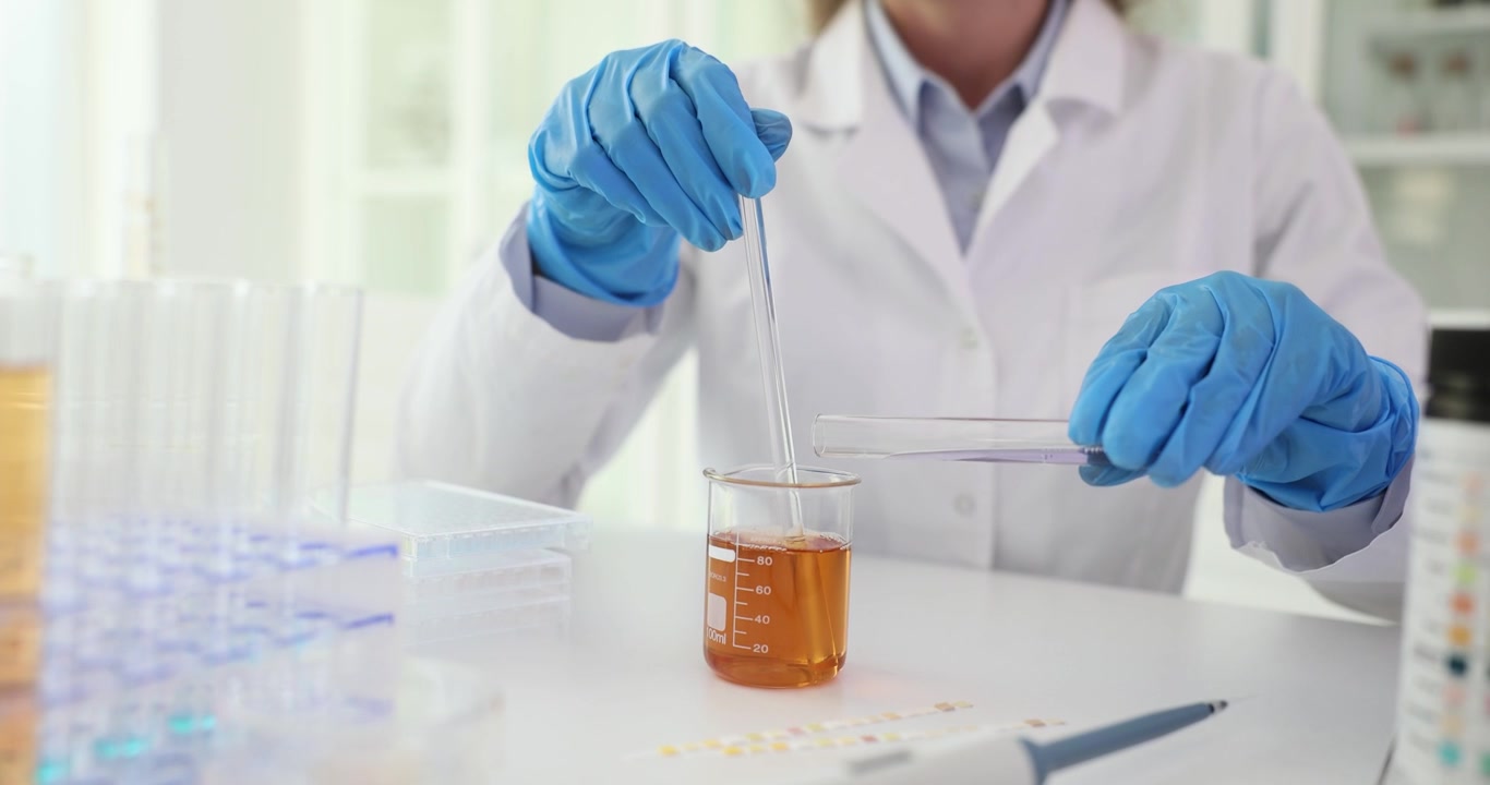 Female scientist blends chemical solution in glass beaker