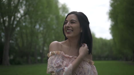 gorgeous and playful hispanic brunette modeling and waving goodbye, smiling with a floral dress