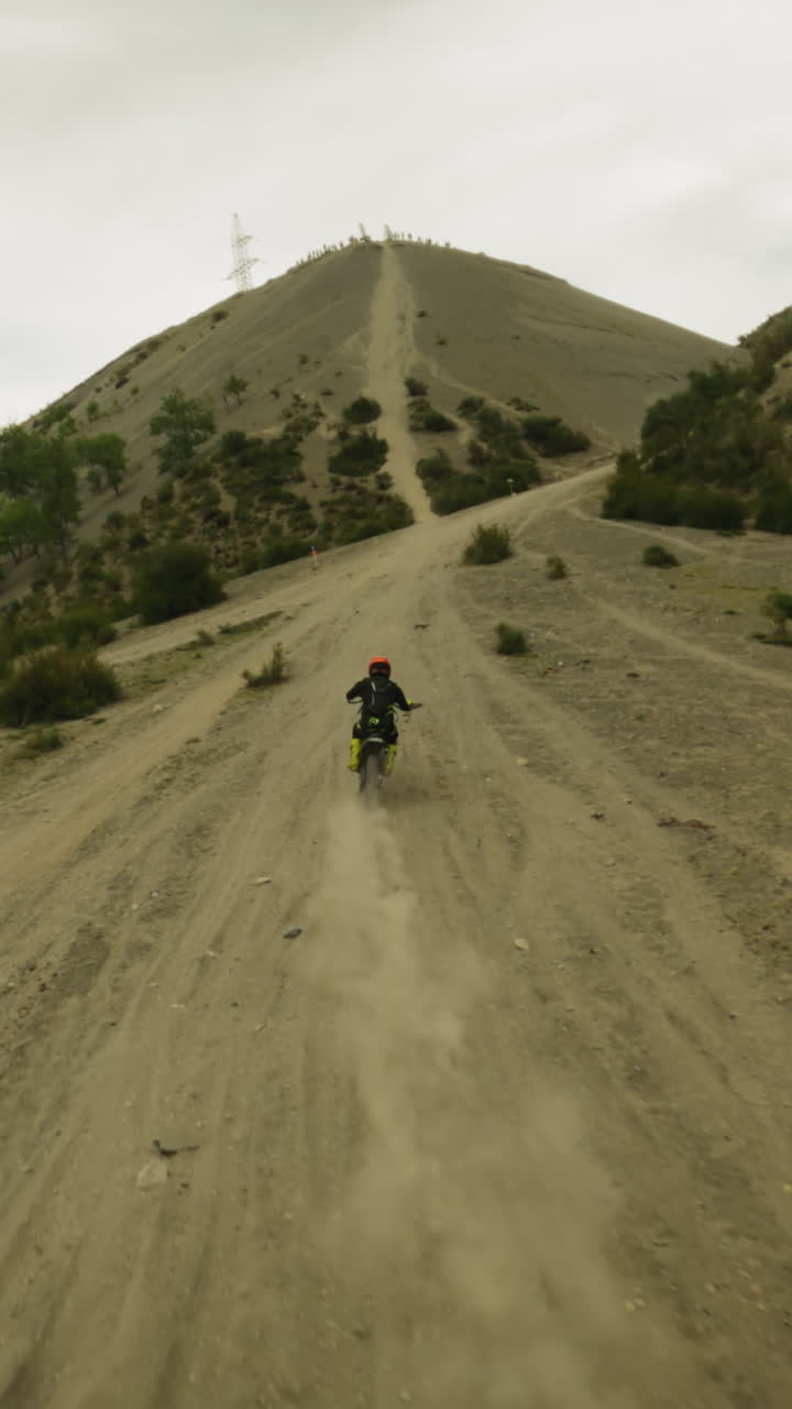 모터사이클리스트는 언덕 계곡에서 어려운 트랙을 니다. fpv. 스포츠 선수는 고지대에서 먼지로 가득 찬 트레일을 따라 오토바이를 타고 있습니다. 극심한 스포츠 경쟁.