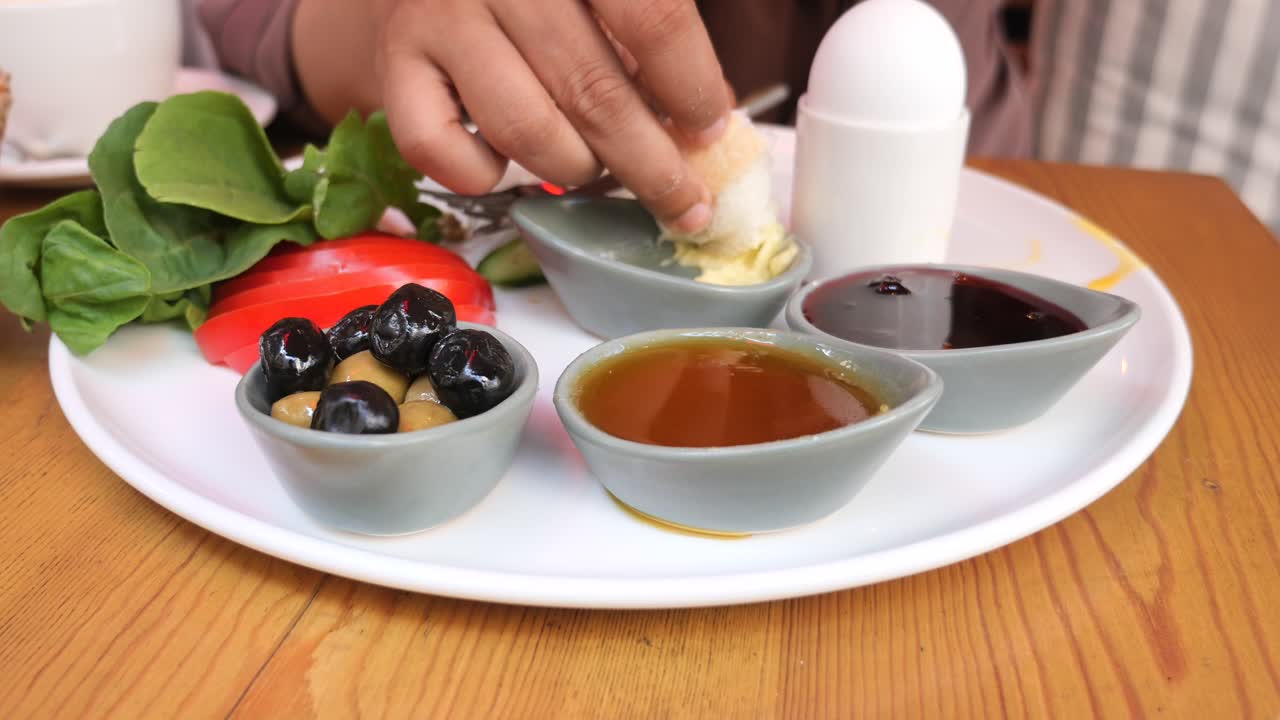 Turkish Breakfast with Bread, Olives, Tomatoes, Lettuce, Egg, Honey, Butter and Jam
