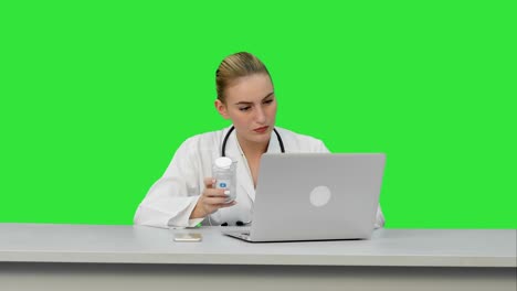 portrait of a nurse studing new pills using laptop computer on a green screen, chroma key
